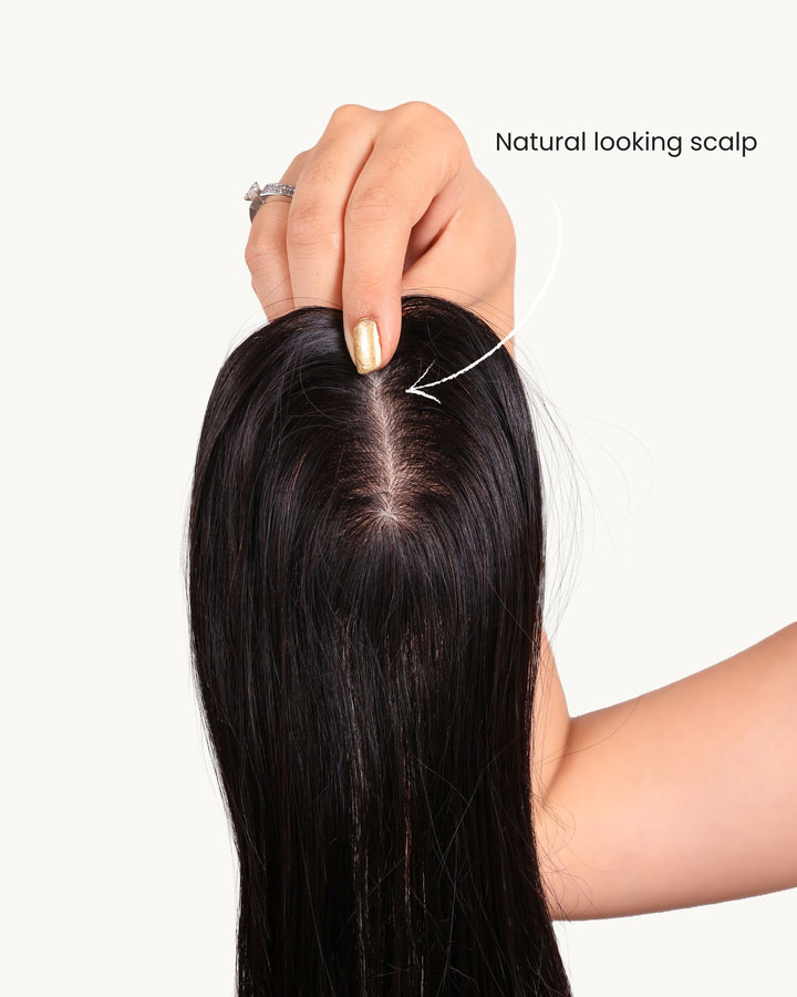 Close-up of a hand touching a natural-looking scalp with hair extensions.
